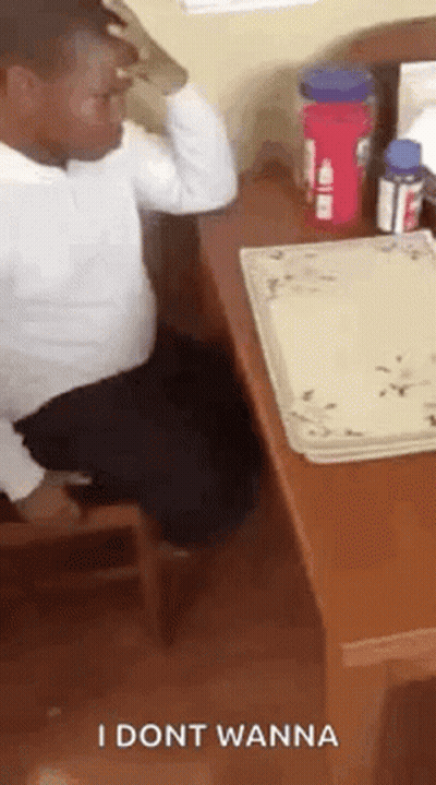 A Man Is Sitting At A Desk With A Plate On It And A Bottle Of Water . GIF