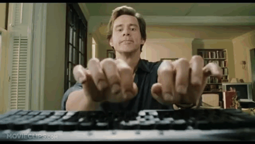 A Man Is Sitting At A Keyboard With His Hands Up . GIF