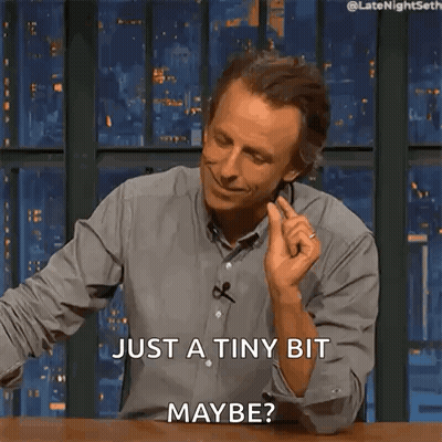 A Man Is Sitting At A Table And Smiling And Says Just A Tiny Bit Maybe GIF