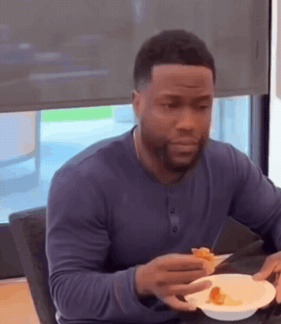 A Man Is Sitting At A Table Eating A Slice Of Pizza . GIF
