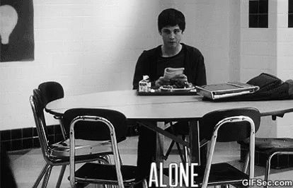 A Man Is Sitting At A Table In A Cafeteria Alone . GIF