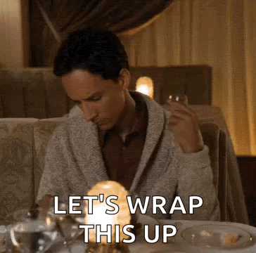 A Man Is Sitting At A Table In A Restaurant Holding A Glass Of Wine And A Candle . GIF