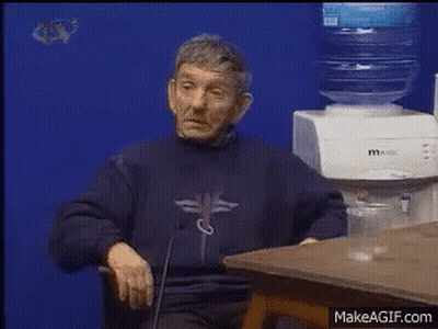 A Man Is Sitting At A Table In Front Of A Water Dispenser GIF