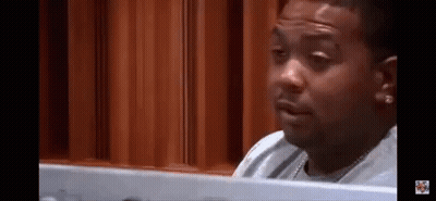 A Man Is Sitting At A Table Looking At A Computer Screen And Making A Funny Face . GIF