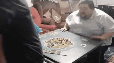 A Man Is Sitting At A Table Playing A Game . GIF