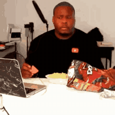 A Man Is Sitting At A Table With A Bag Of Doritos On It GIF