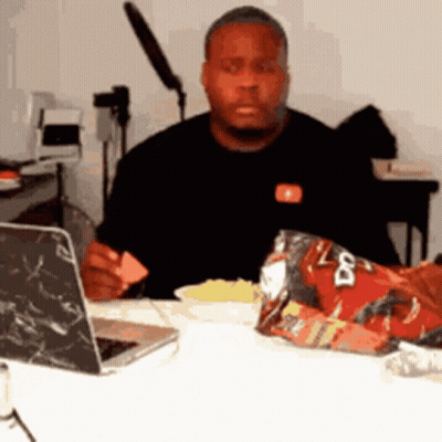 A Man Is Sitting At A Table With A Bag Of Doritos On It GIF