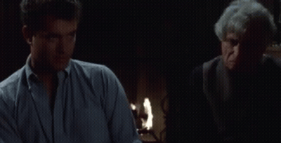 A Man Is Sitting At A Table With A Bowl Of Pretzels In Front Of Him GIF