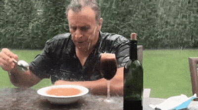 A Man Is Sitting At A Table With A Bowl Of Soup And A Bottle Of Wine .. GIF