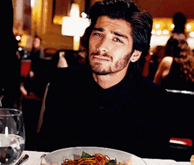 A Man Is Sitting At A Table With A Bowl Of Spaghetti On It GIF
