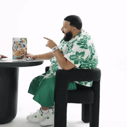 A Man Is Sitting At A Table With A Box Of Cereal GIF
