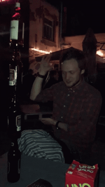A Man Is Sitting At A Table With A Box Of Uno Chips GIF