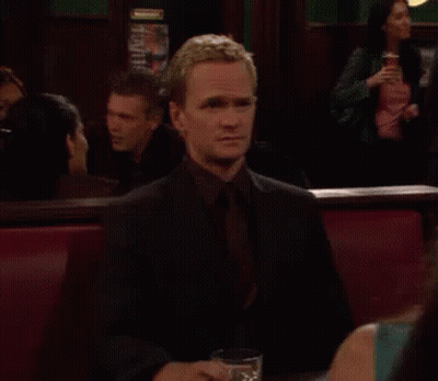 A Man Is Sitting At A Table With A Glass Of Whiskey In Front Of Him GIF