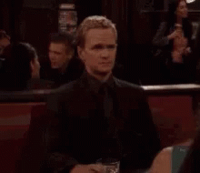 A Man Is Sitting At A Table With A Glass Of Wine And A Plate Of Food . GIF
