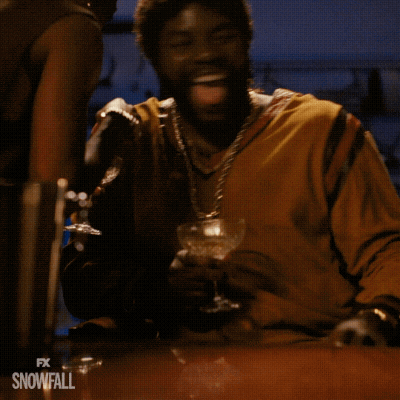A Man Is Sitting At A Table With A Glass Of Wine In His Hand And The Words Fx Snowfall On The Bottom Right GIF