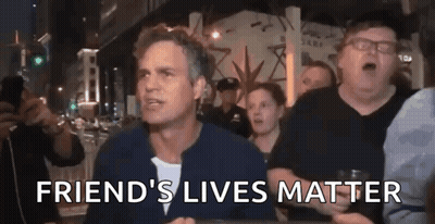 A Man Is Sitting At A Table With A Group Of People And The Words `` Friend 'S Lives Matter '' Written On It . GIF