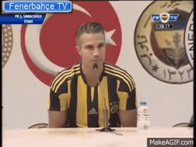 A Man Is Sitting At A Table With A Microphone In Front Of Him . GIF