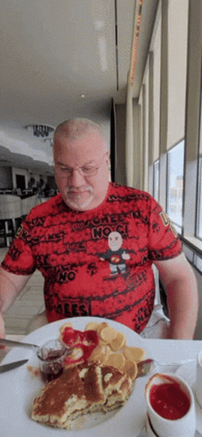 A Man Is Sitting At A Table With A Plate Of Food And A T-Shirt That Says " No " GIF