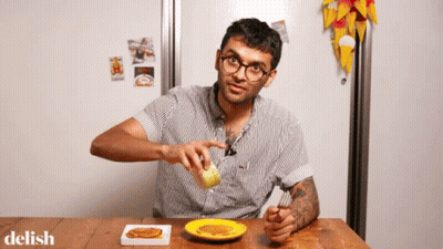 A Man Is Sitting At A Table With A Plate Of Food And The Word Delish On The Bottom Right GIF