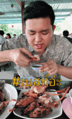 A Man Is Sitting At A Table With A Plate Of Food In Front Of Him And The Word # On The Bottom Right GIF