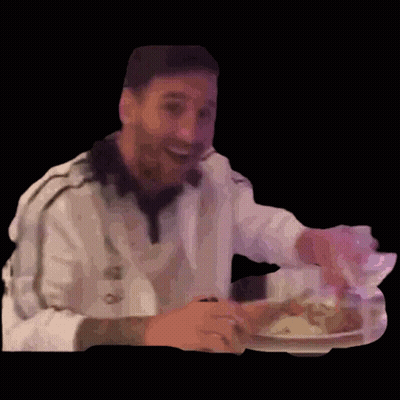 A Man Is Sitting At A Table With A Plate Of Food In His Hand . GIF