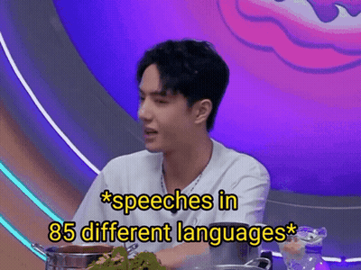 A Man Is Sitting At A Table With A Pot Of Food And The Words Speeches In 85 Different Languages Above Him GIF