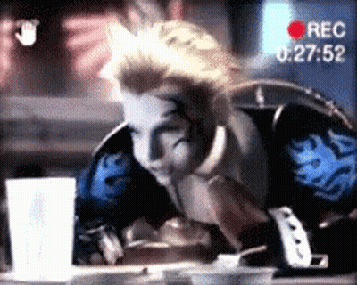 A Man Is Sitting At A Table With A Recorder Recording Him At 00:27:52 GIF