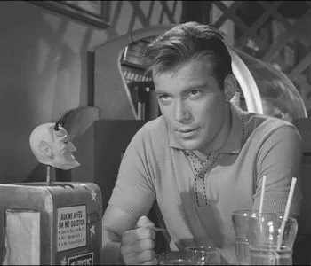 A Man Is Sitting At A Table With A Sign That Says Ask Me A Yes On No Question GIF