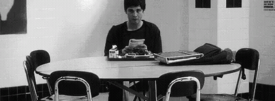 A Man Is Sitting At A Table With A Tray Of Food . GIF