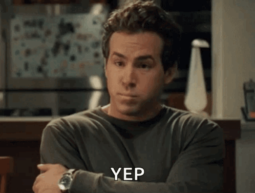 A Man Is Sitting At A Table With His Arms Crossed And The Word Yep Is On The Screen . GIF