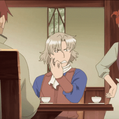 A Man Is Sitting At A Table With His Hand On His Mouth GIF