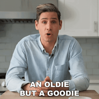 A Man Is Sitting At A Table With The Words An Oldie But A Goodie Behind Him GIF