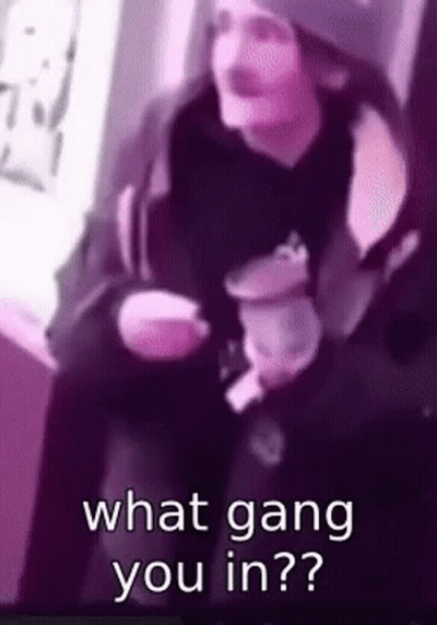 A Man Is Sitting Down Holding A Cup Of Coffee And Asking What Gang You Are In . GIF