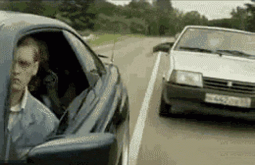 A Man Is Sitting In A Car Next To A White Car With A License Plate That Starts With Nc GIF