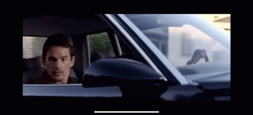 A Man Is Sitting In A Car With A Gun On The Windshield GIF