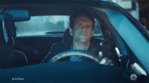 A Man Is Sitting In A Car With His Hand Out The Window And Waving . GIF