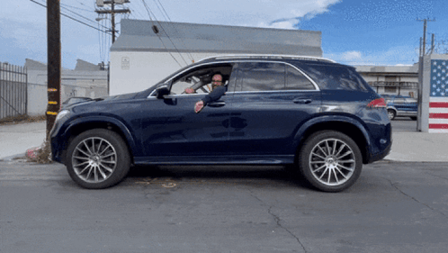 A Man Is Sitting In A Car With His Hand Out The Window GIF