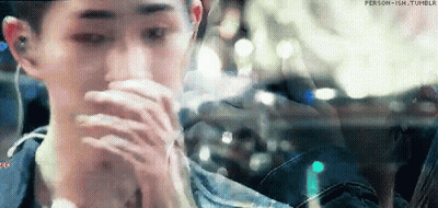 A Man Is Sitting In A Car With His Hands On His Face And Looking Out The Window . GIF