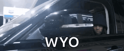 A Man Is Sitting In A Car With The Word Wyo Written On The Side GIF