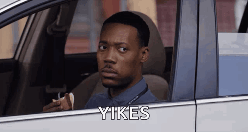 A Man Is Sitting In A Car With The Word Yikes On The Side GIF