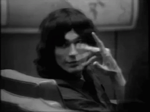 A Man Is Sitting In A Chair And Making A Peace Sign With His Hand . GIF