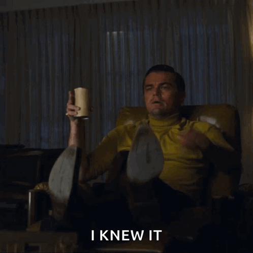 A Man Is Sitting In A Chair And Pointing At Something With The Words I Knew It Above Him GIF