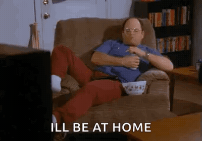 A Man Is Sitting In A Chair Eating Popcorn And Drinking Beer While Watching Television . GIF
