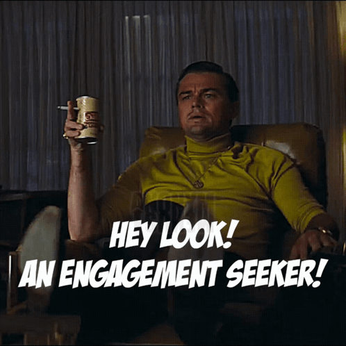 A Man Is Sitting In A Chair Holding A Can Of Beer And Pointing At Something With The Words Hey Look An Engagement Seeker GIF