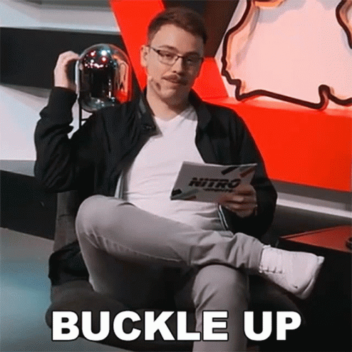 A Man Is Sitting In A Chair Holding A Helmet And A Book That Says Buckle Up On It . GIF