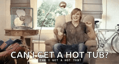 A Man Is Sitting In A Chair In A Living Room Asking Can I Get A Hot Tub . GIF