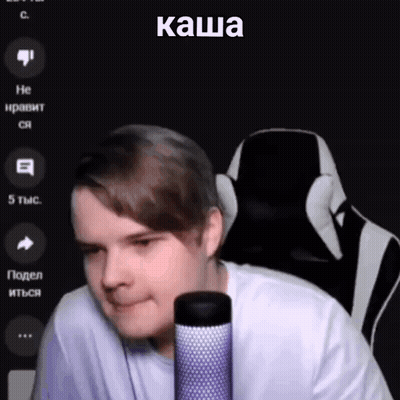 A Man Is Sitting In A Chair In Front Of A Microphone With A Foreign Language On The Screen . GIF