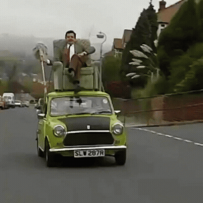 A Man Is Sitting In A Chair On Top Of A Green Car . GIF