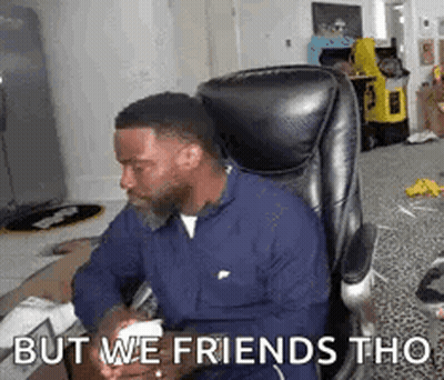 A Man Is Sitting In A Chair Playing A Video Game With The Words `` But We Friends Tho '' Written On The Screen . GIF