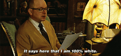 A Man Is Sitting In A Chair Reading A Piece Of Paper And Says It Says Here That I Am 100 % White GIF
